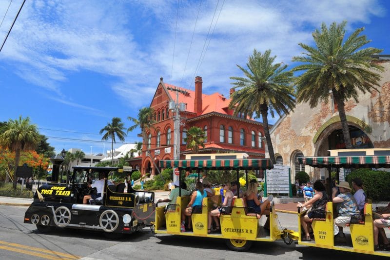 A group of people are riding a train down a street.