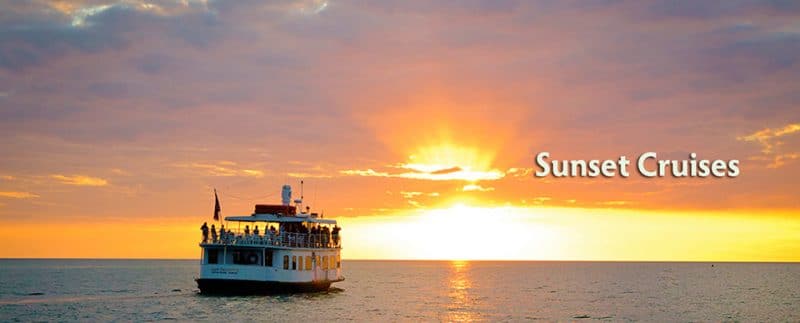 A boat is floating in the ocean at sunset.