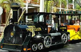 A small train is parked on the side of the road.