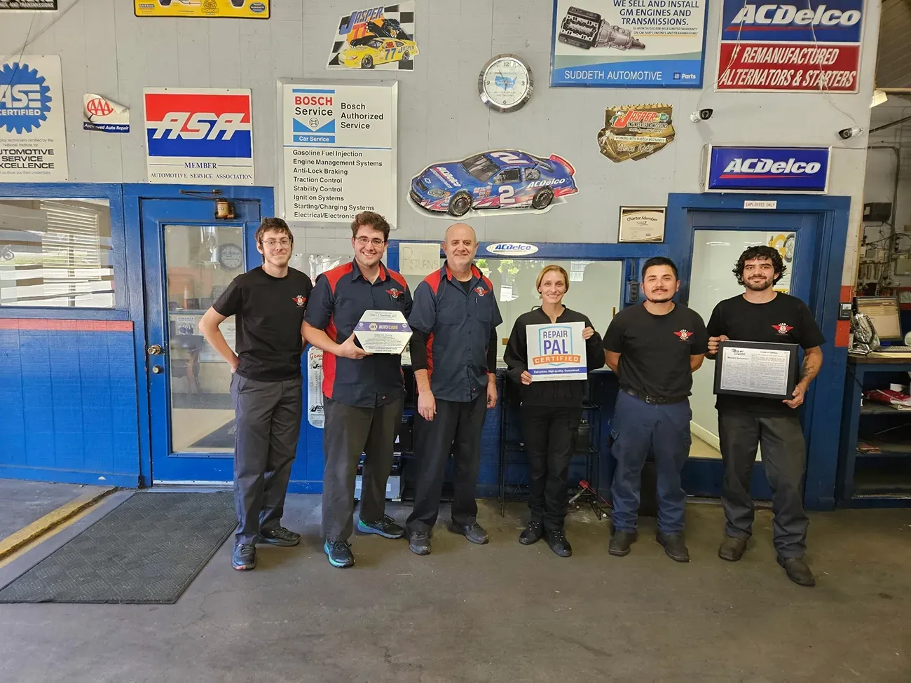 Our team inside our shop with our rewards and certifications | Team One Suddeth Automotive