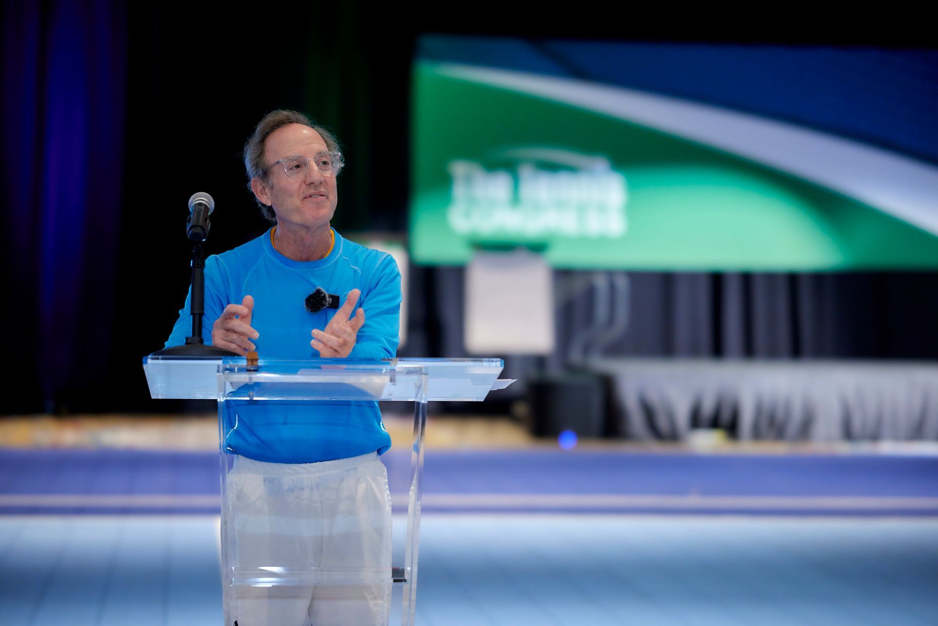 Man in blue shirt speaks at podium, 