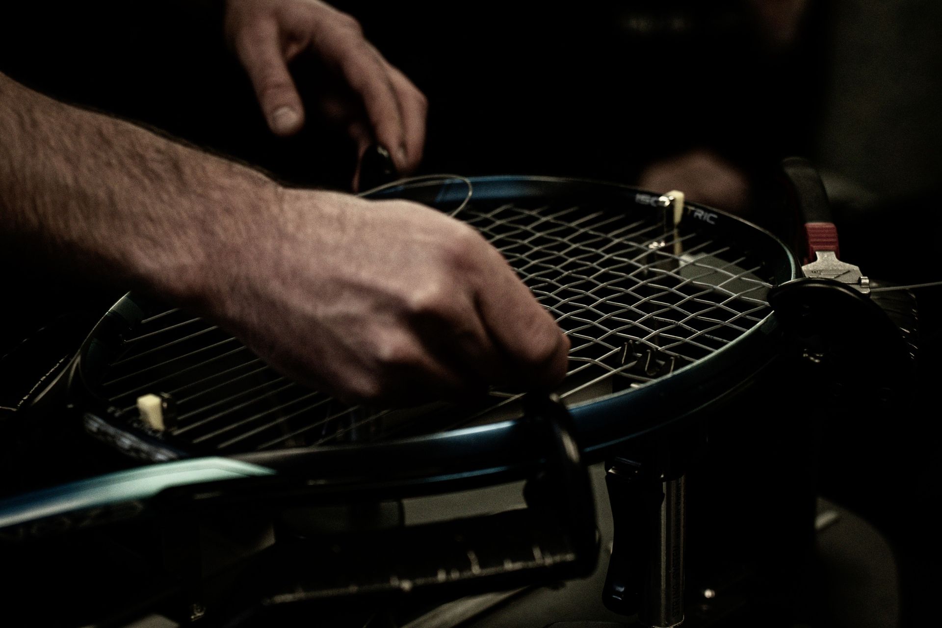 Tennis player restringing a tennis racquet on a professional stringing machine.