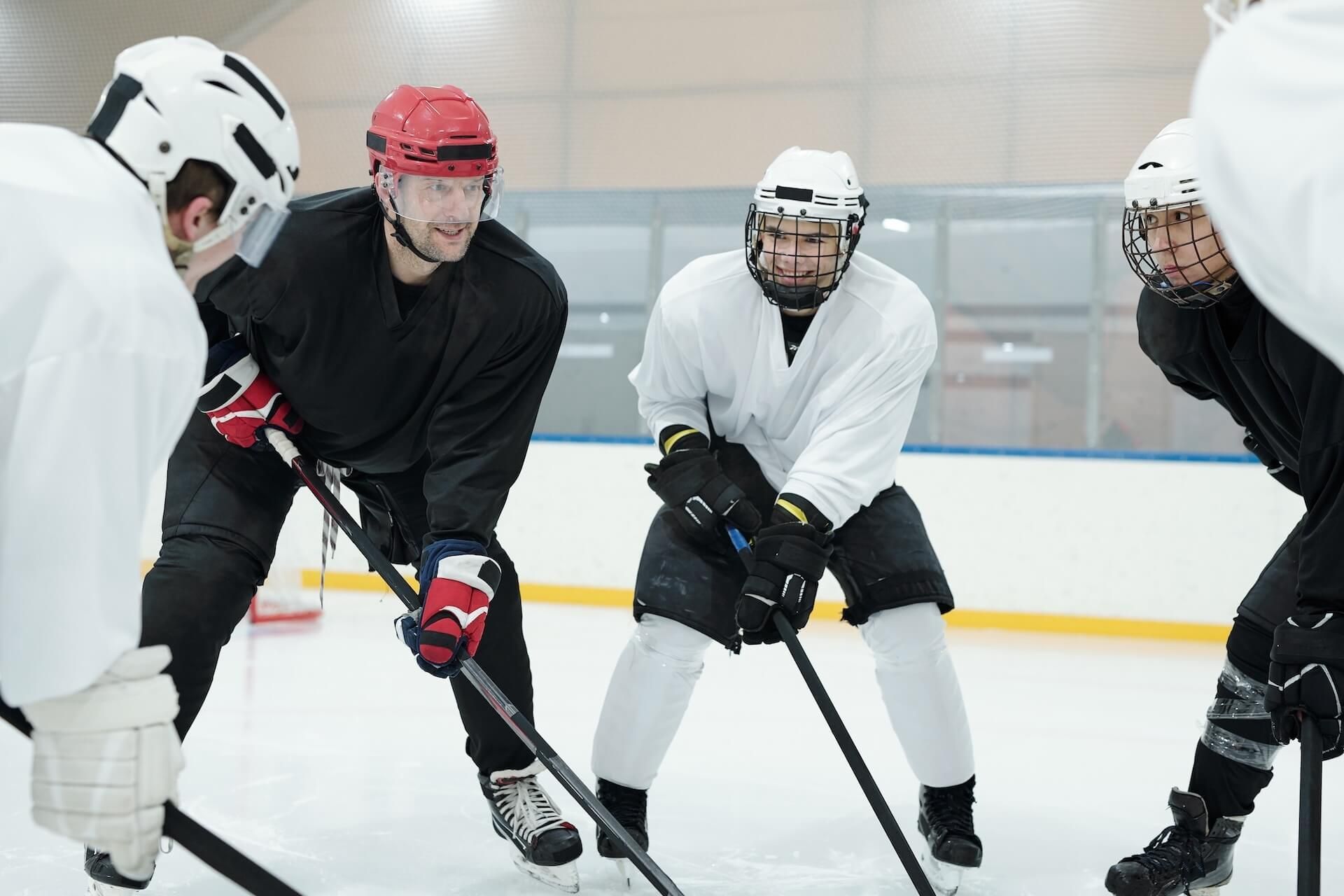 Hockey players in white and black gear face off on an indoor ice rink.