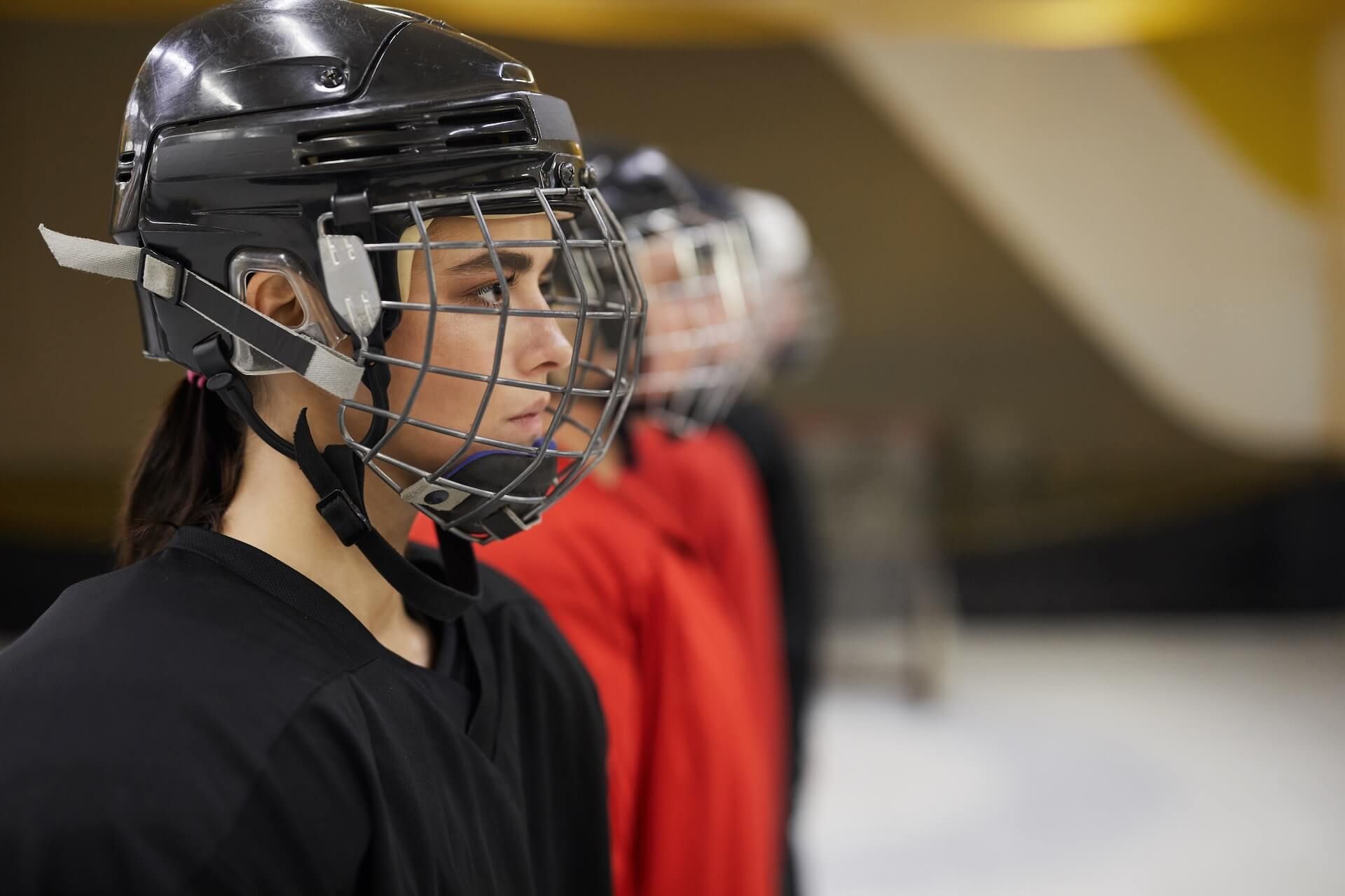 Ice hockey player in black helmet and jersey, seen in profile on the rink.