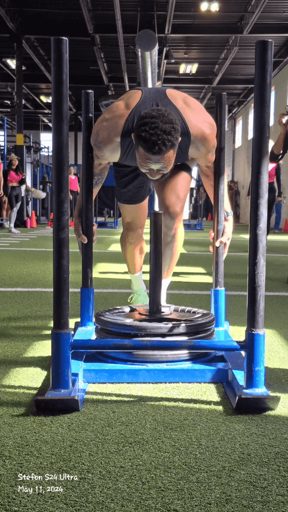 Athlete pushing a sled on indoor turf during a gym workout