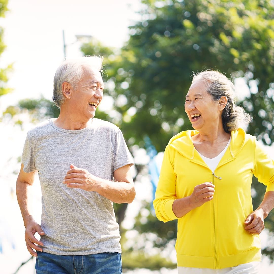 A Man And A Woman Are Walking Together And Smiling — Sea & Sand Chiropractic In Toukley, NSW