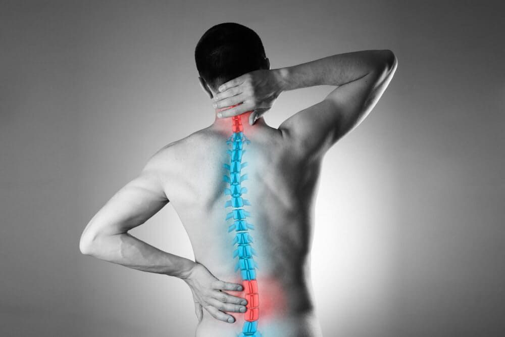 A Man Is Holding His Back In Pain While His Spine Is Highlighted In Red And Blue — Sea & Sand Chiropractic In Toukley, NSW