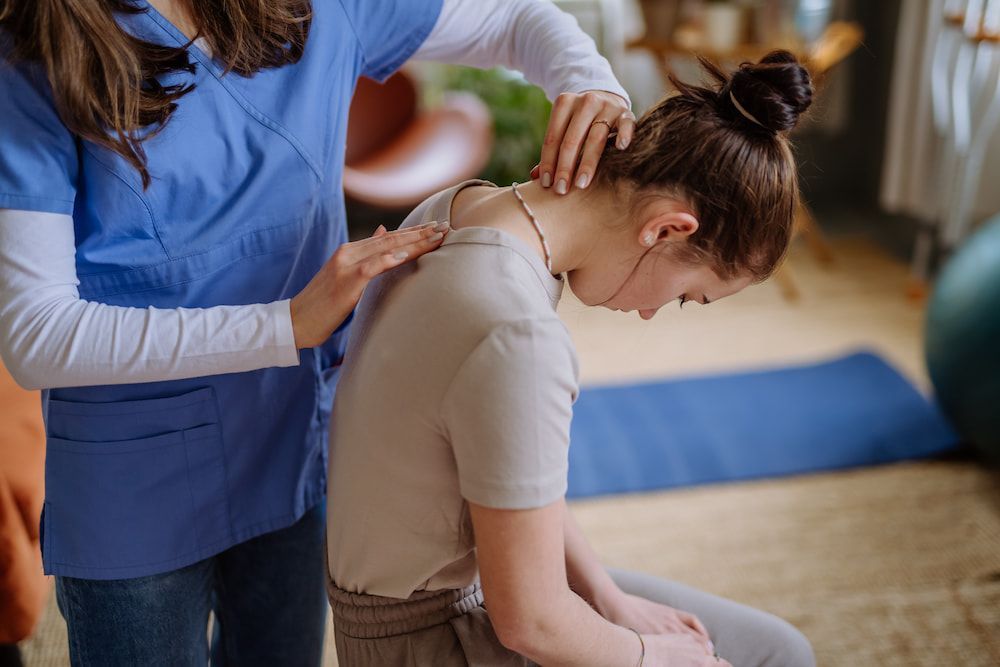 A Woman Is Getting A Massage From A Nurse In A Living Room — Sea & Sand Chiropractic In Toukley, NSW