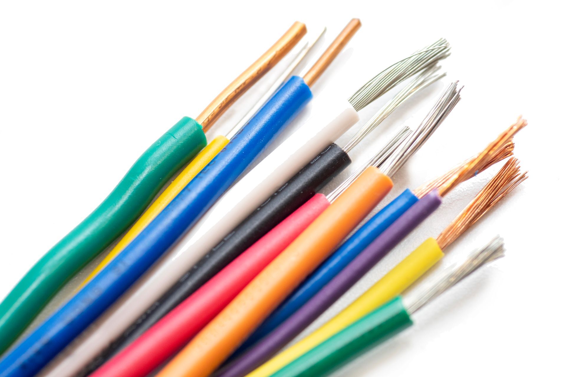 Cables eléctricos de colores variados con extremos de cobre expuestos sobre un fondo blanco.