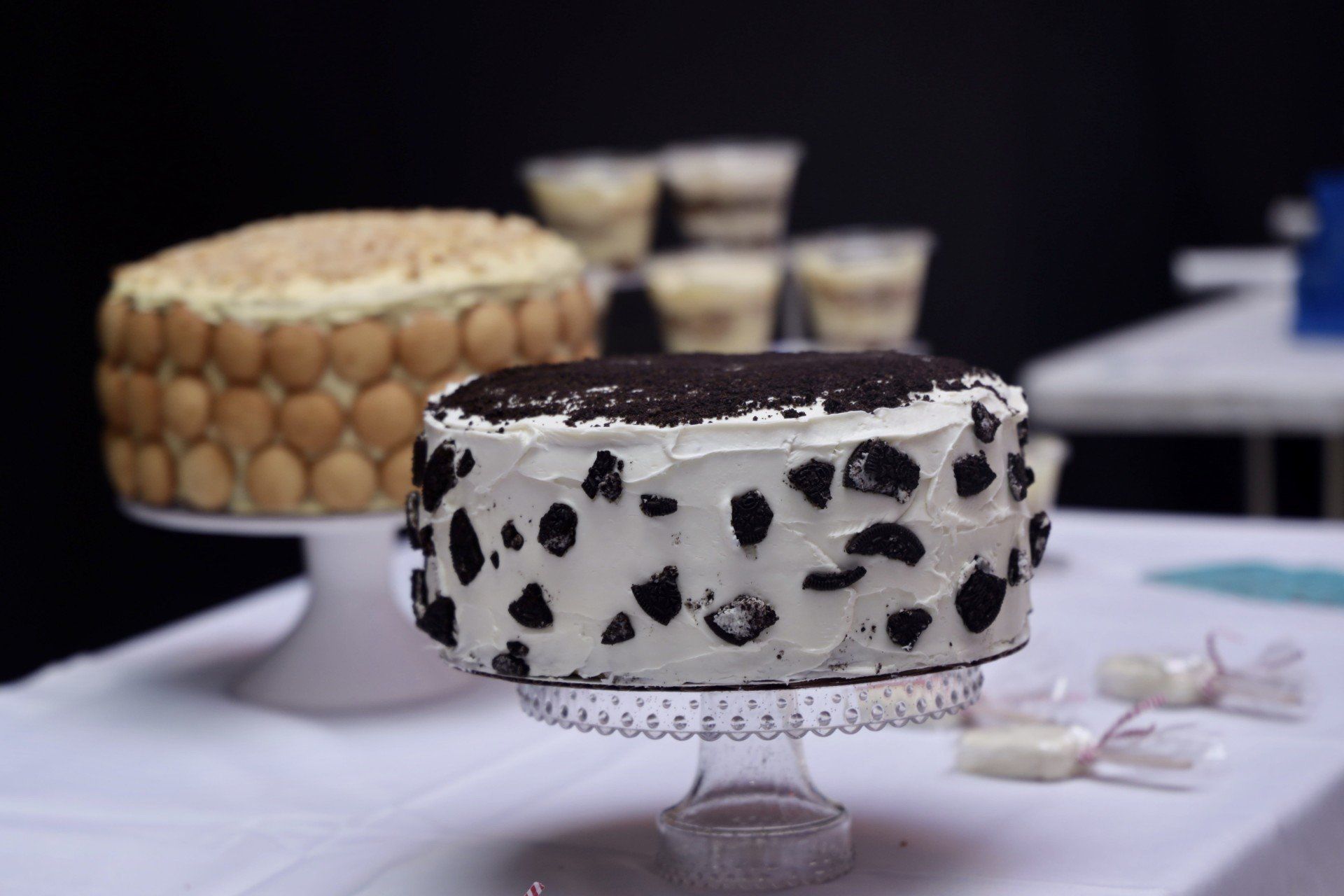 Two decorated cakes on stands, including a black-and-white spotted cake in front.
