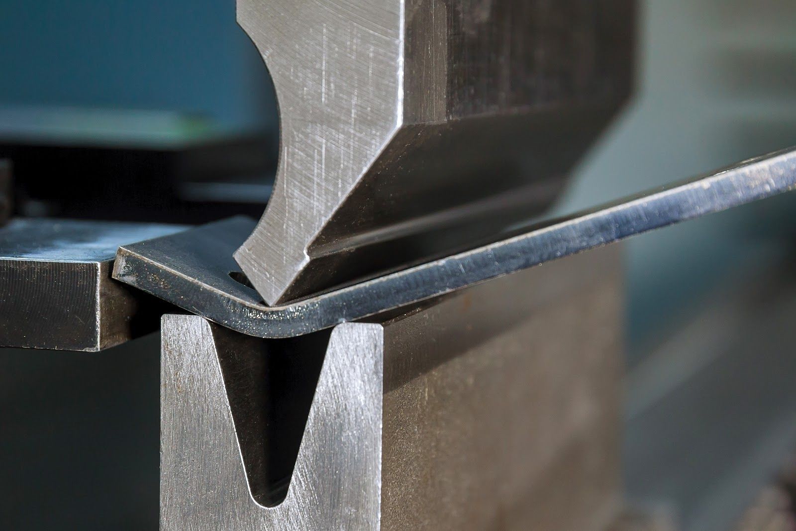 Metal sheet being bent by a press brake machine.