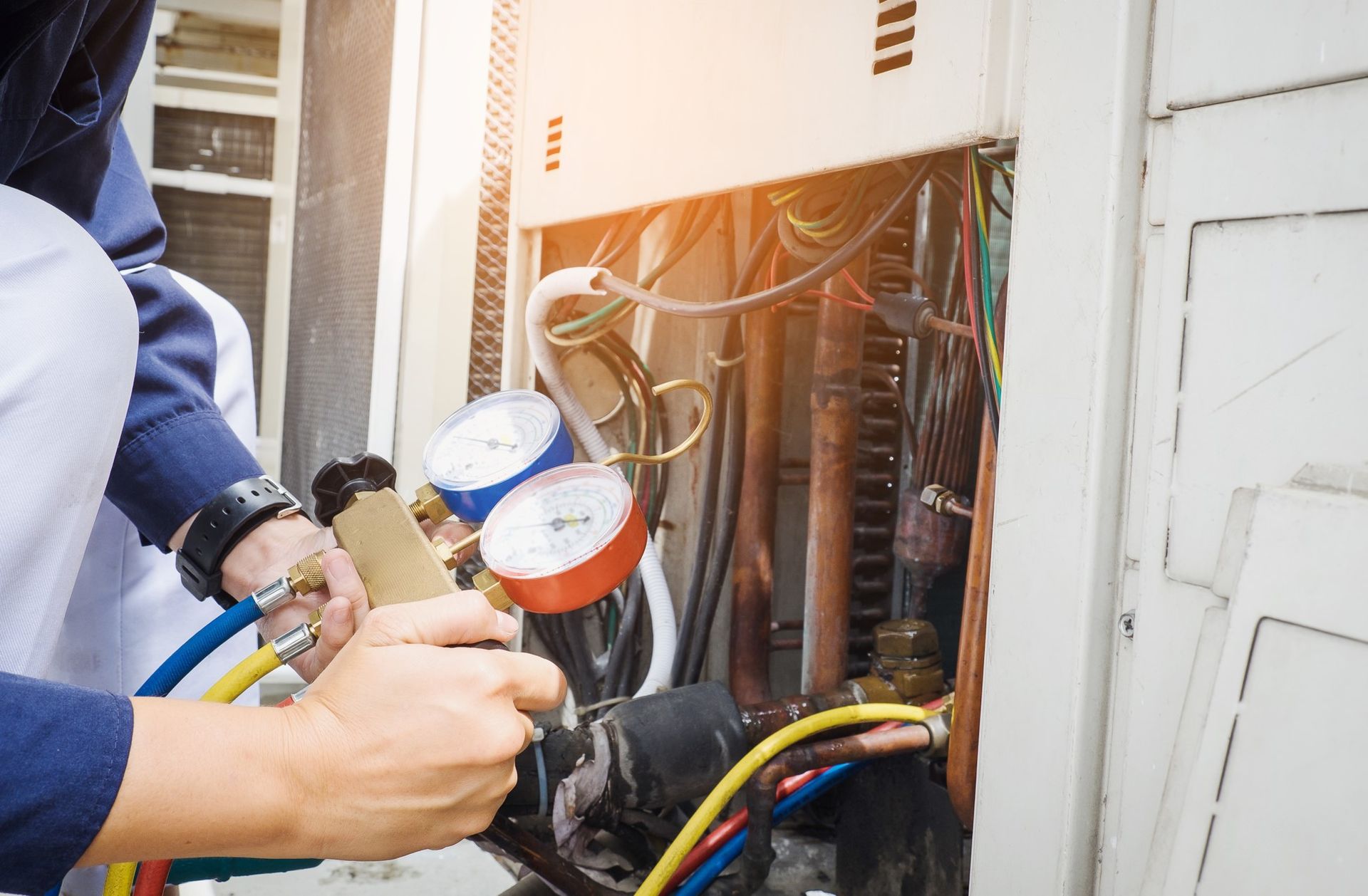 Technician using gauges on exposed electrical wiring in an open utility panel