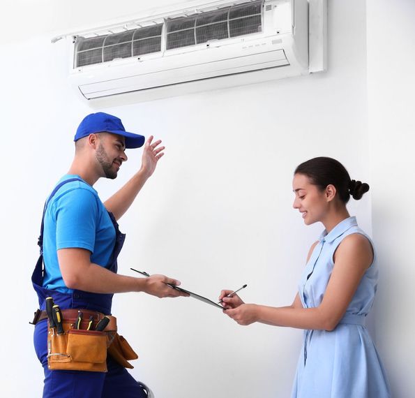 HVAC technician discussing an air conditioner repair with a woman indoors