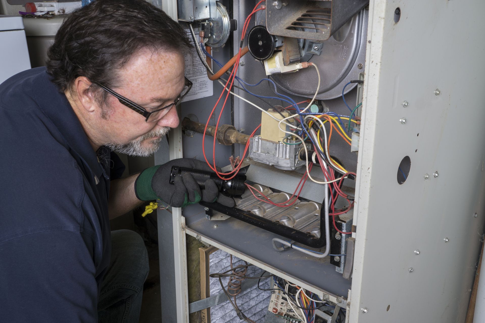 Technician inspecting wiring inside an open electrical control panel.