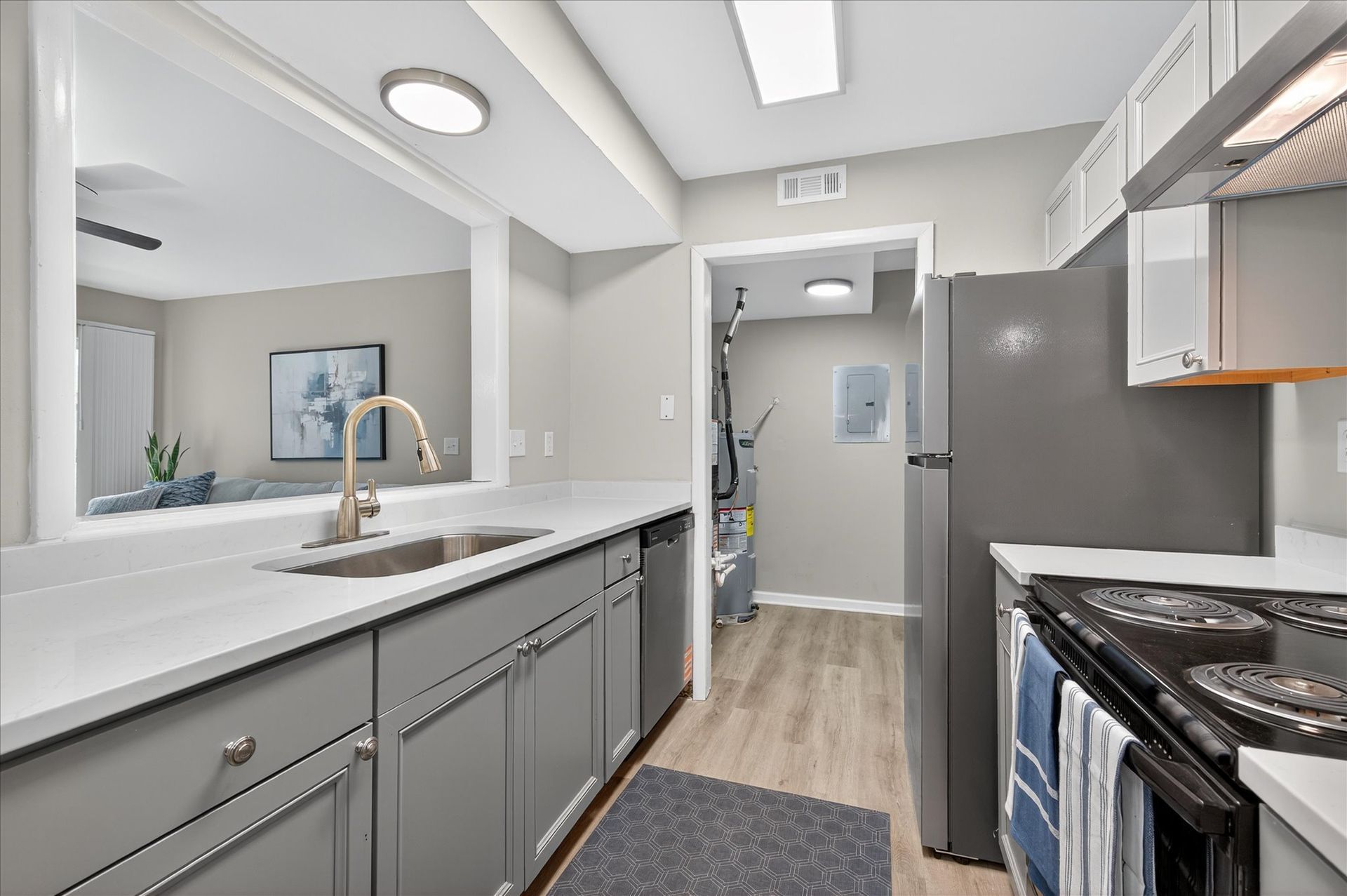 Modern kitchen with gray cabinets, white countertops, stainless appliances, and light wood flooring