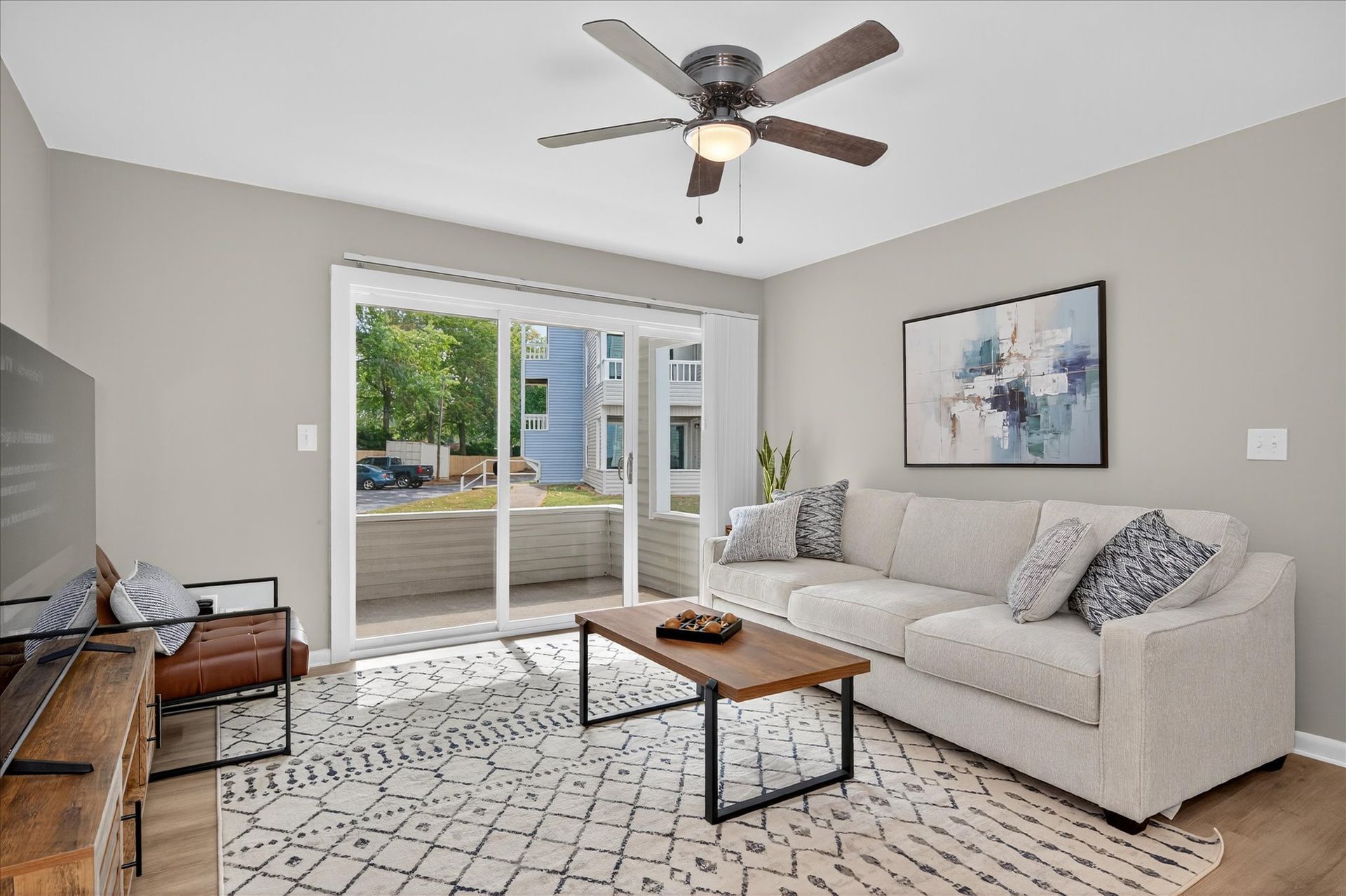 Bright living room with beige sofa, patterned rug, coffee table, and sliding doors to a deck