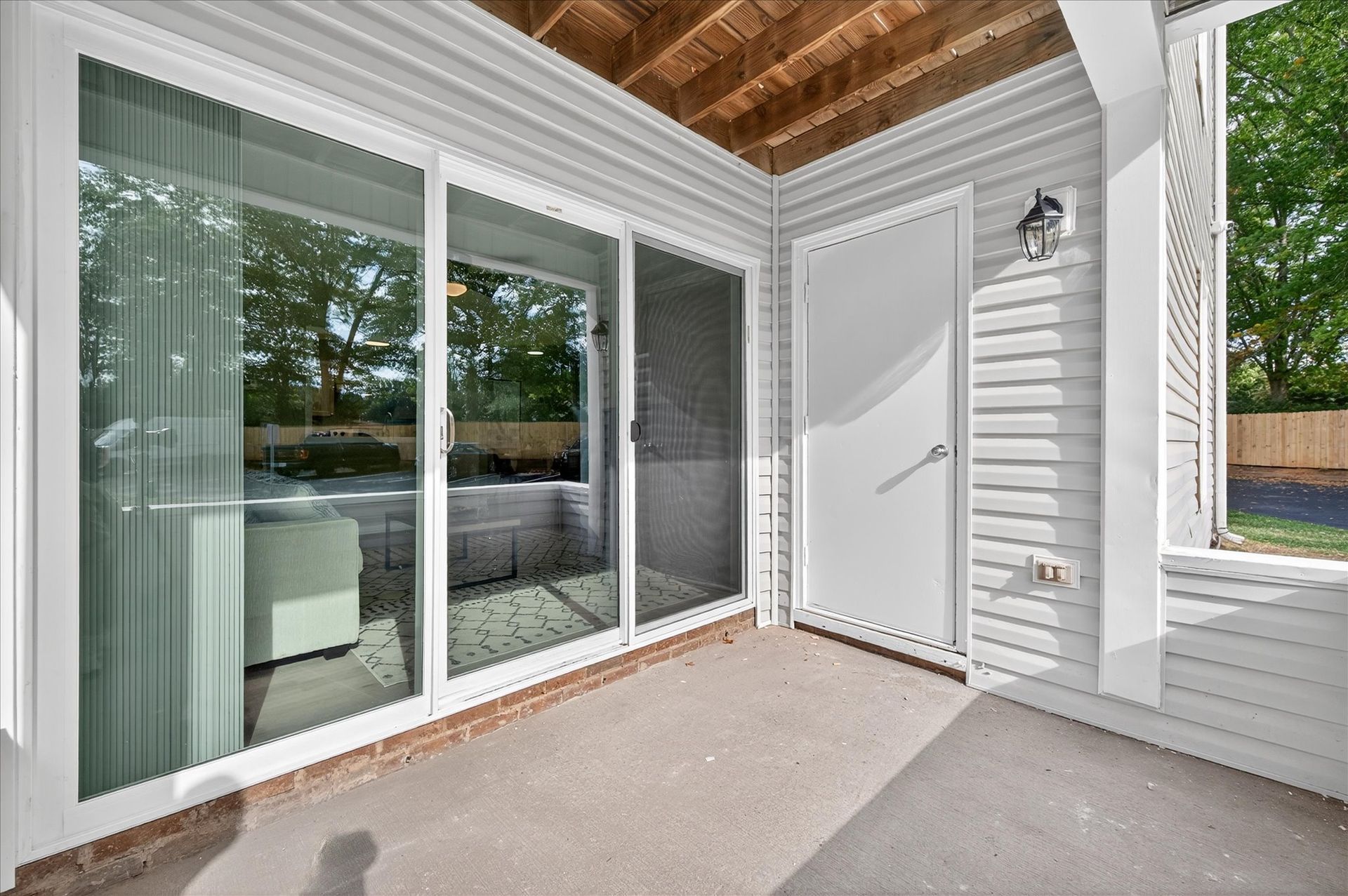 Covered patio with sliding glass door, white siding, and concrete floor