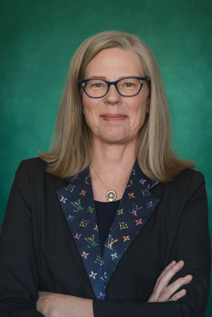 A woman wearing glasses and a blue jacket is sitting in a car. sloan johnson