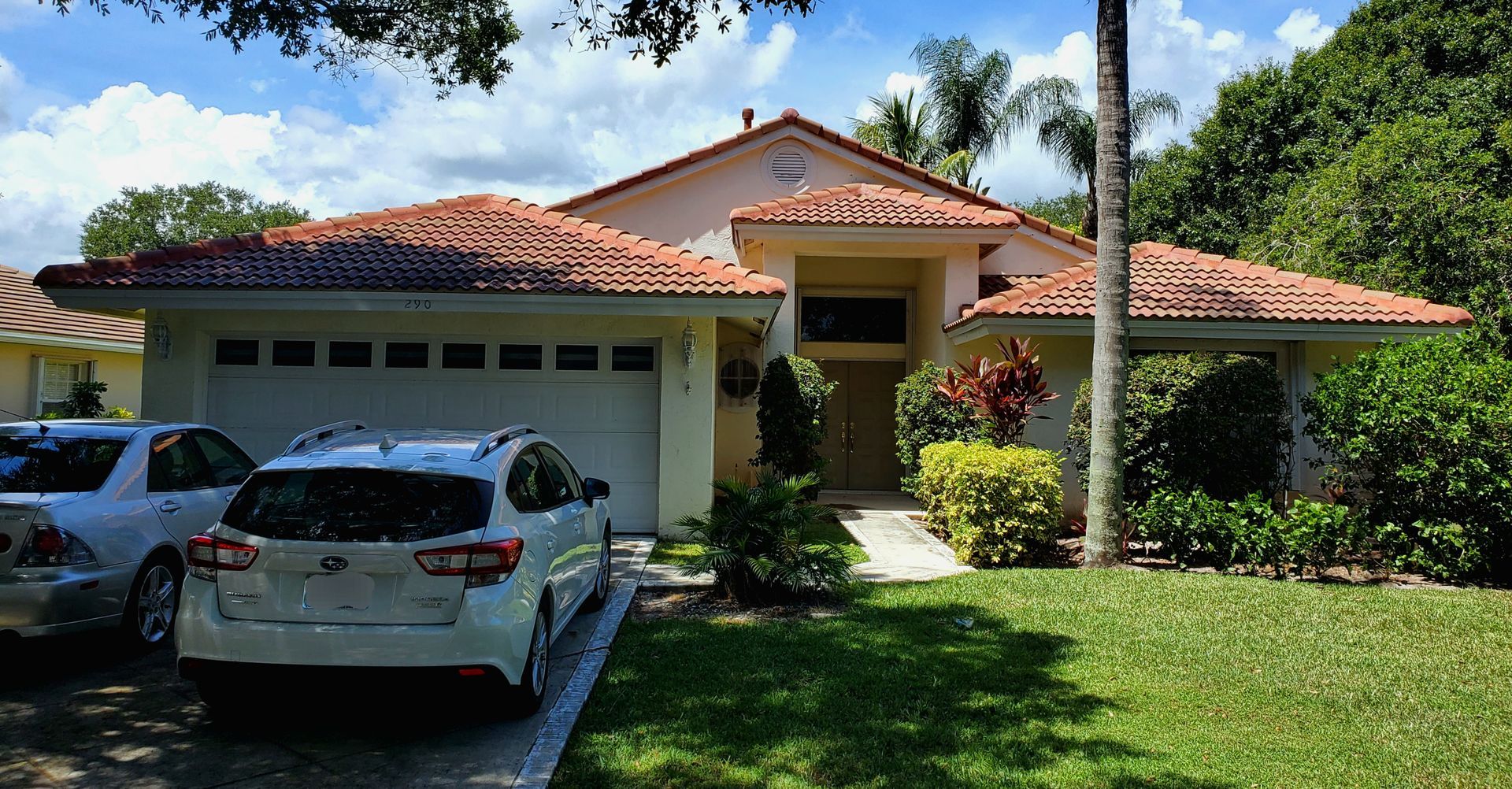 A white suv is parked in front of a large house.