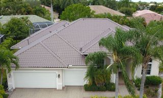 An aerial view of a house with a tiled roof surrounded by palm trees.