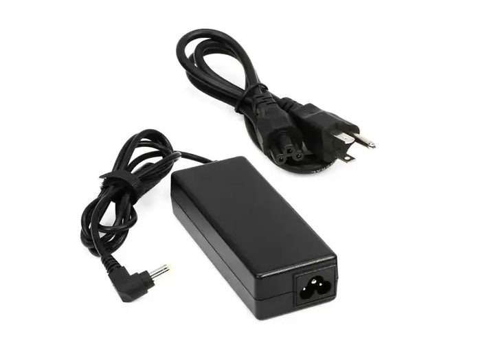 Adaptador de corriente negro para portátil con cables y enchufe conectados sobre un fondo blanco.
