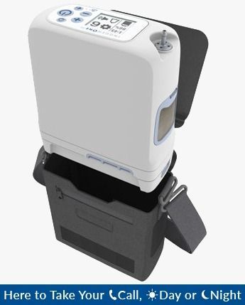 Dispositivo de audición asistida blanco y negro con pantalla y controles, montado sobre un soporte con bolsa de transporte.