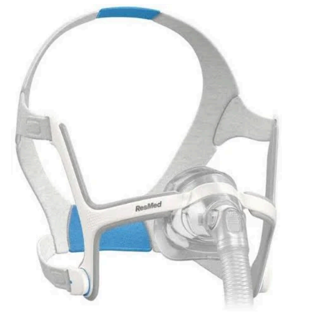 Mascarilla facial completa CPAP blanca y azul con conexión de manguera sobre un fondo liso.