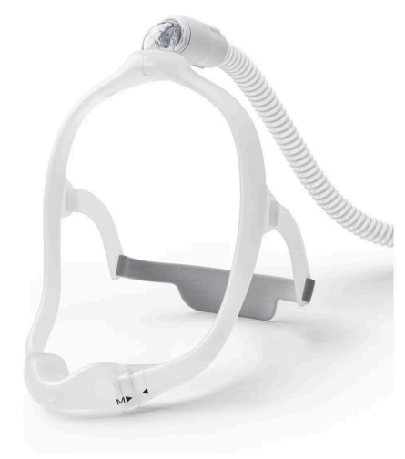 Mascarilla CPAP blanca con arnés y tubo grises sobre fondo blanco.