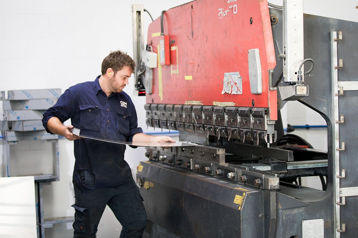 A man is working on a machine in a factory — Sheet Metal Fabrication In Caloundra, Qld