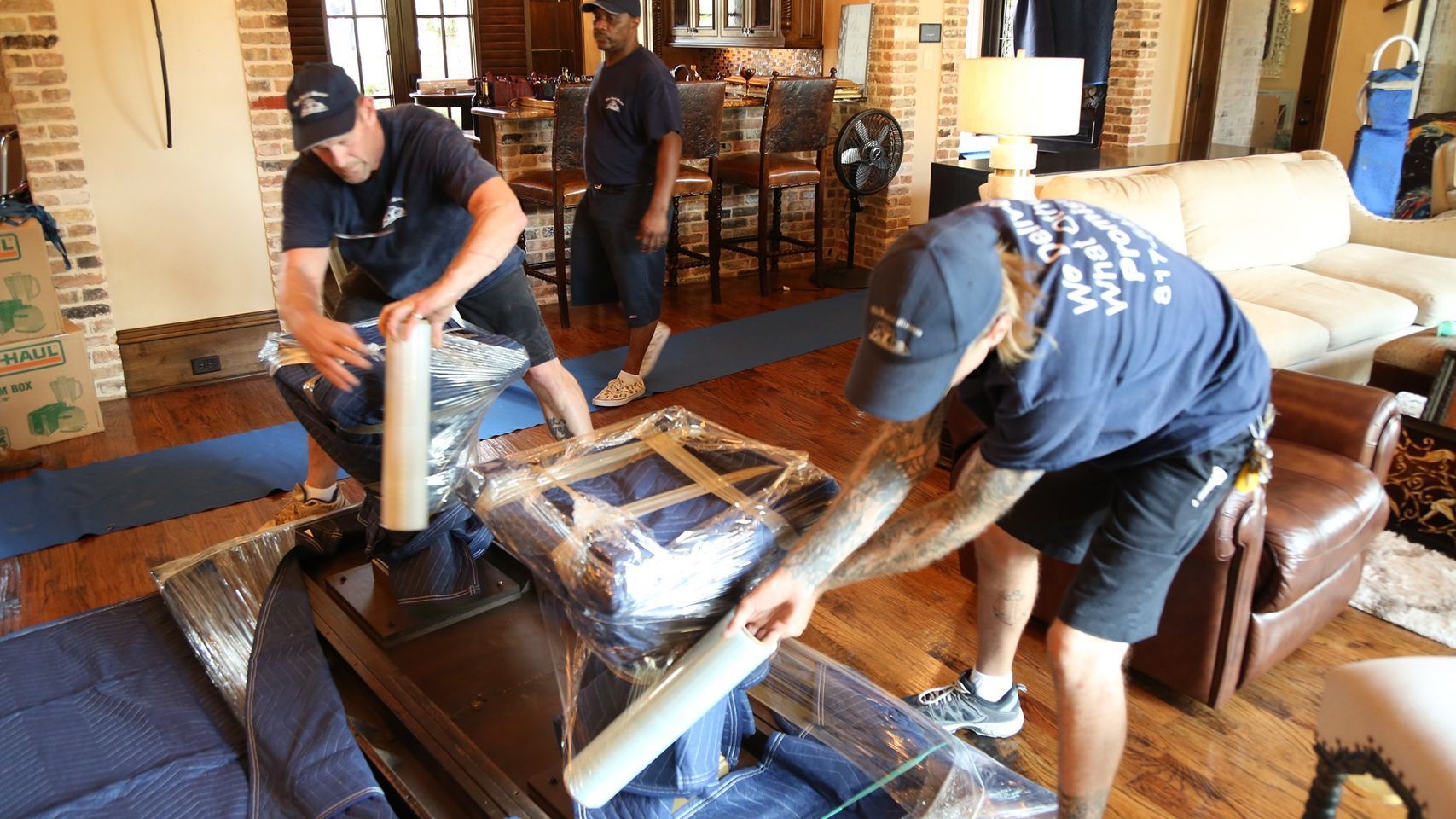 Movers Wrapping Furniture in A Living Room — Barnes Transport and Removals in Wardell, NSW