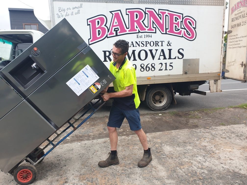 Man in Work Clothes Pushing a Refrigerator on A Dolly — Barnes Transport and Removals in Wardell, NSW