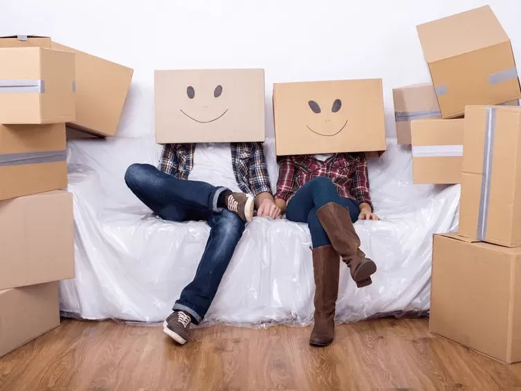 Two People Sit on A Couch with Boxes on Their Heads and Around Them — Barnes Transport and Removals in Ballina, NSW