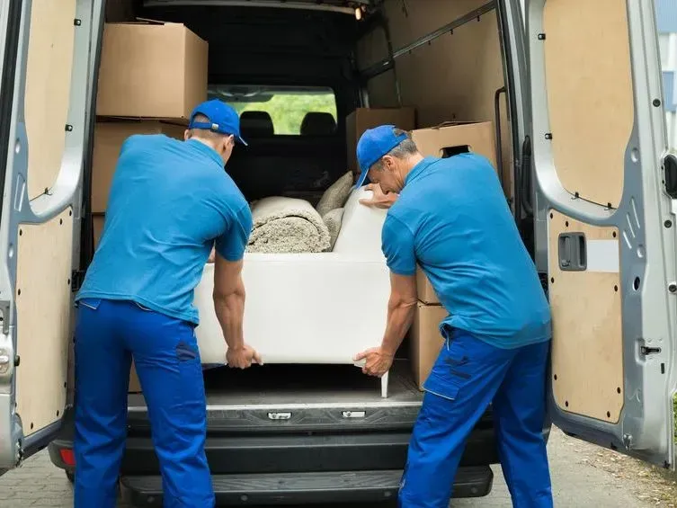 Two Movers in Blue Uniforms Loading Furniture Into a Van — Barnes Transport and Removals in Byron Bay, NSW