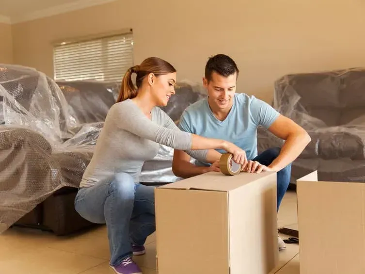 Couple Taping a Cardboard Box While Moving — Barnes Transport and Removals in Lismore, NSW