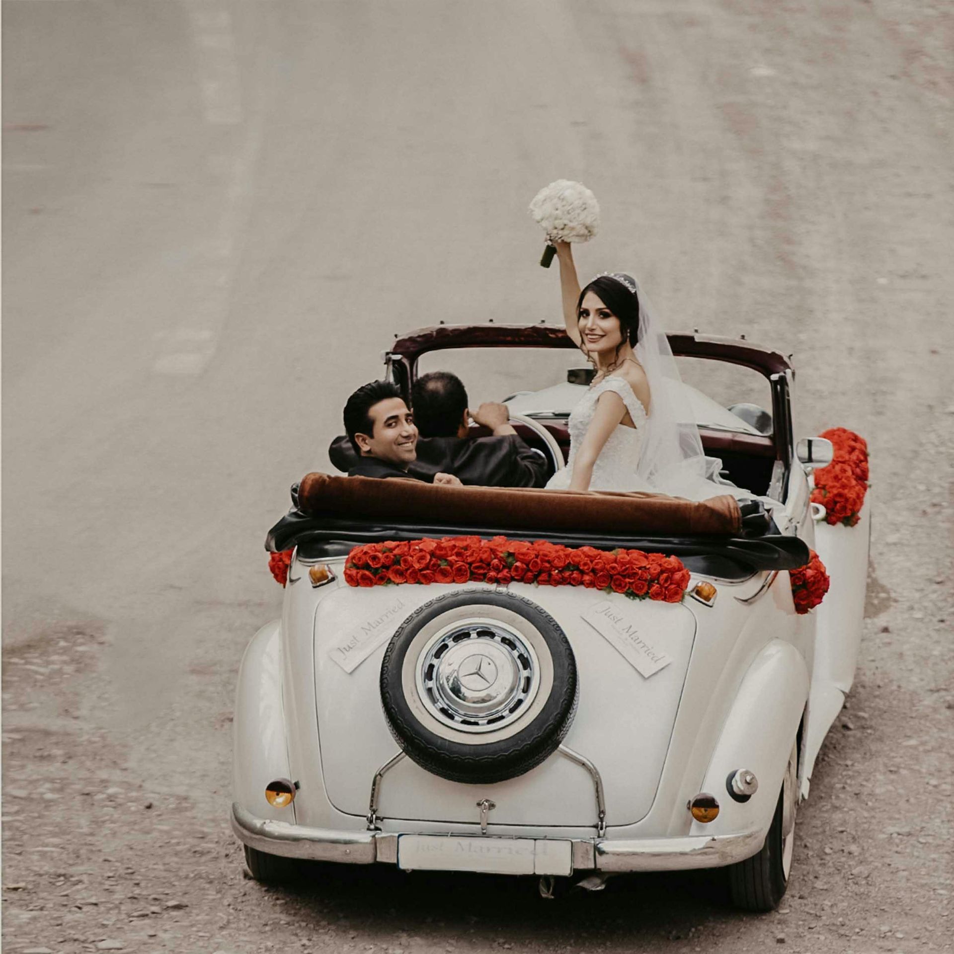 Bruidspaar rijdt samen in een feestelijk versierde auto.