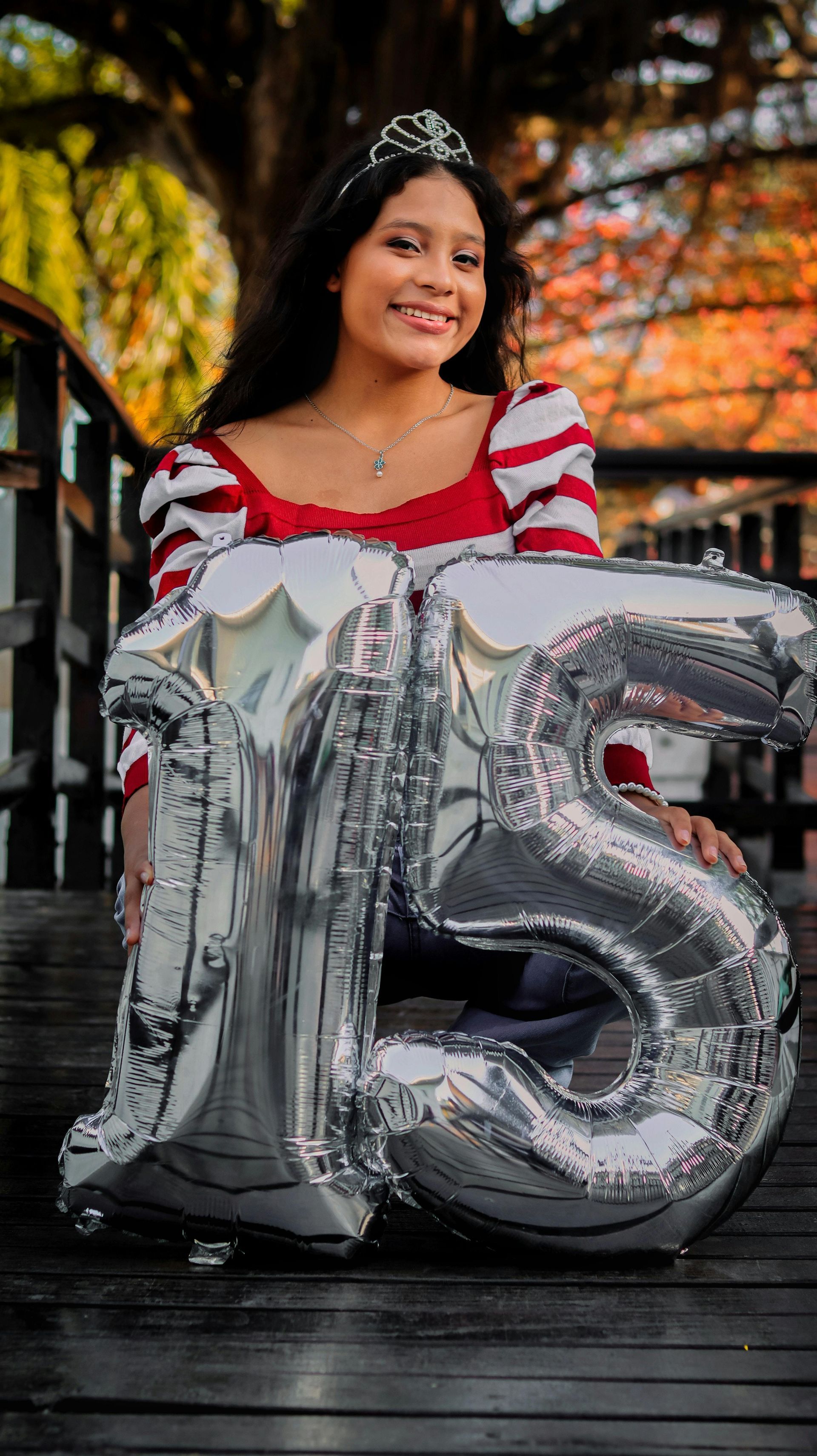Adolescente con tiara, sosteniendo globos 