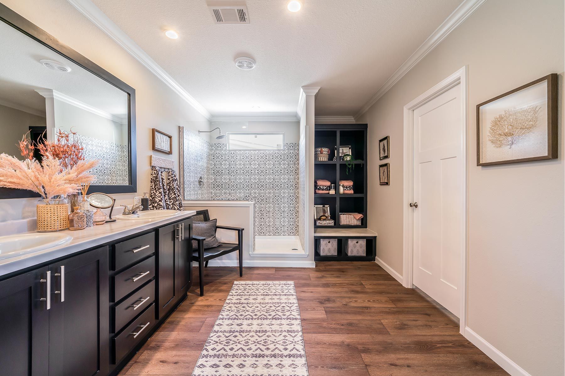 Bright hallway with dark vanity, mirror, bench, patterned rug, and built-in shelves on wood flooring.