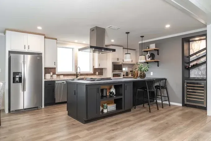 Modern kitchen with dark island, stainless appliances, and light wood floors