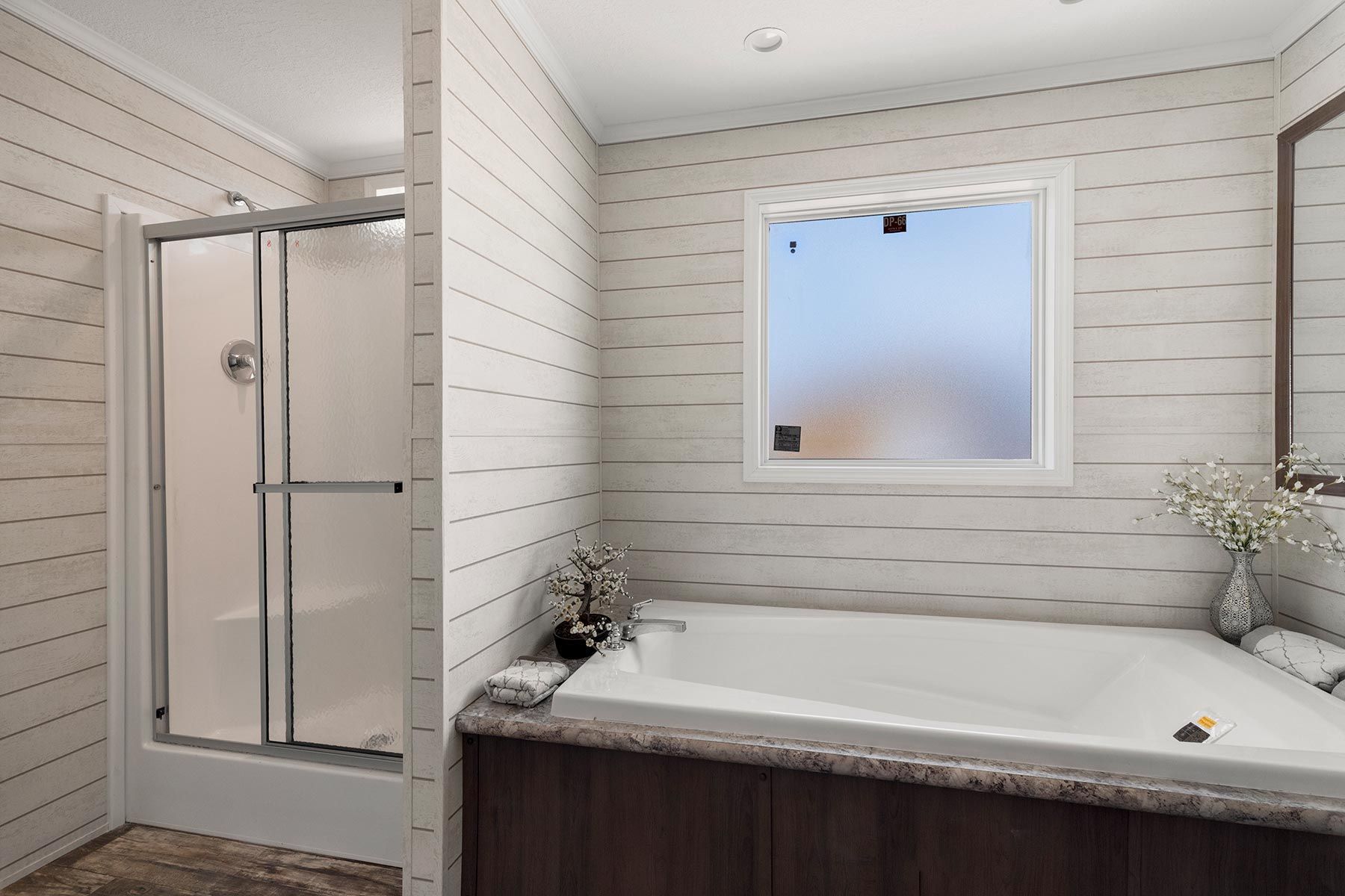 Modern bathroom with a walk-in shower, freestanding tub, and frosted window