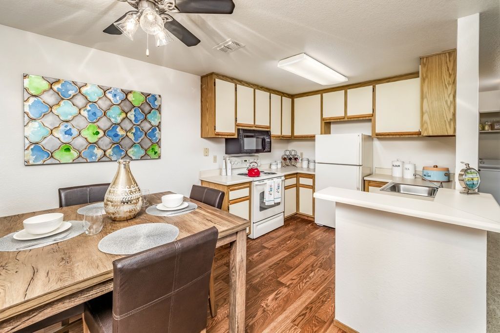 Kitchen and dining area with white appliances, wooden cabinets, and a wooden dining table.