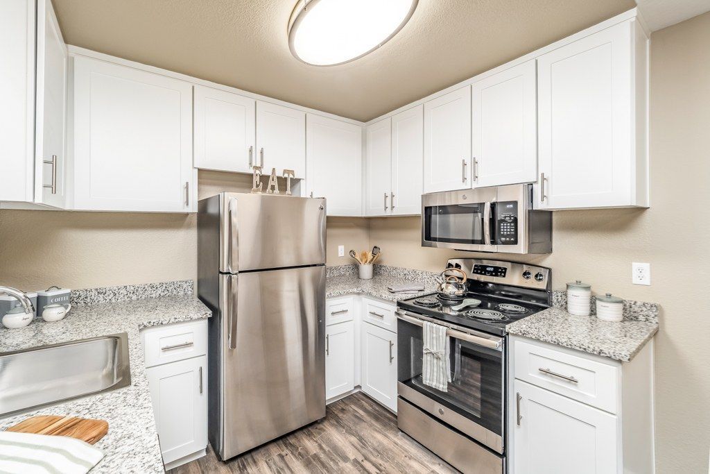 Kitchen with white cabinets, granite countertops, and stainless steel refrigerator, oven, and microwave.