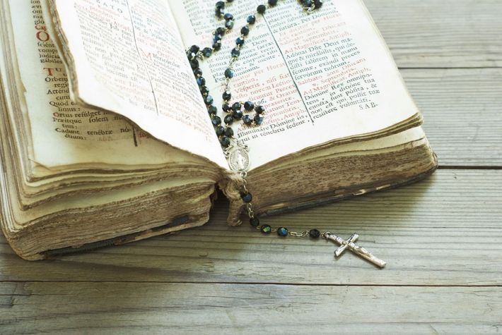Bibbia aperta con rosario e crocifisso d'argento su un tavolo di legno