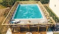 An aerial view of a large swimming pool surrounded by a wooden fence. homestead pool