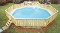 A large swimming pool surrounded by a wooden deck in a backyard.