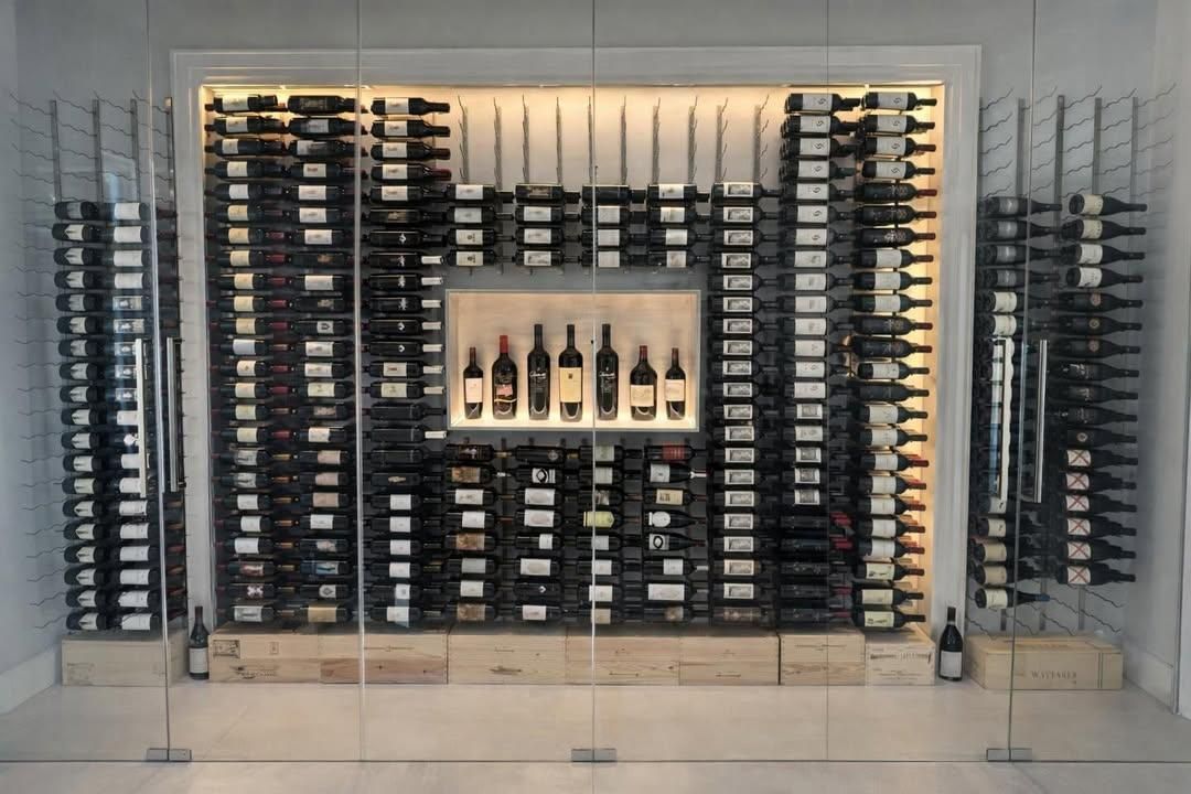 Wine display with rows of bottles on shelves and a central lit niche in a modern cellar