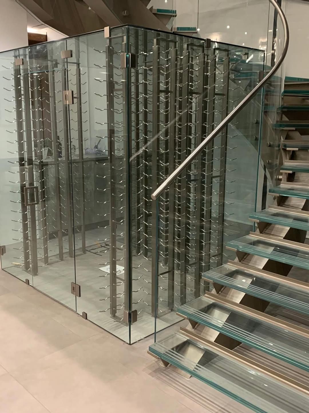 Glass spiral staircase in a modern interior beside clear glass railings and metal steps