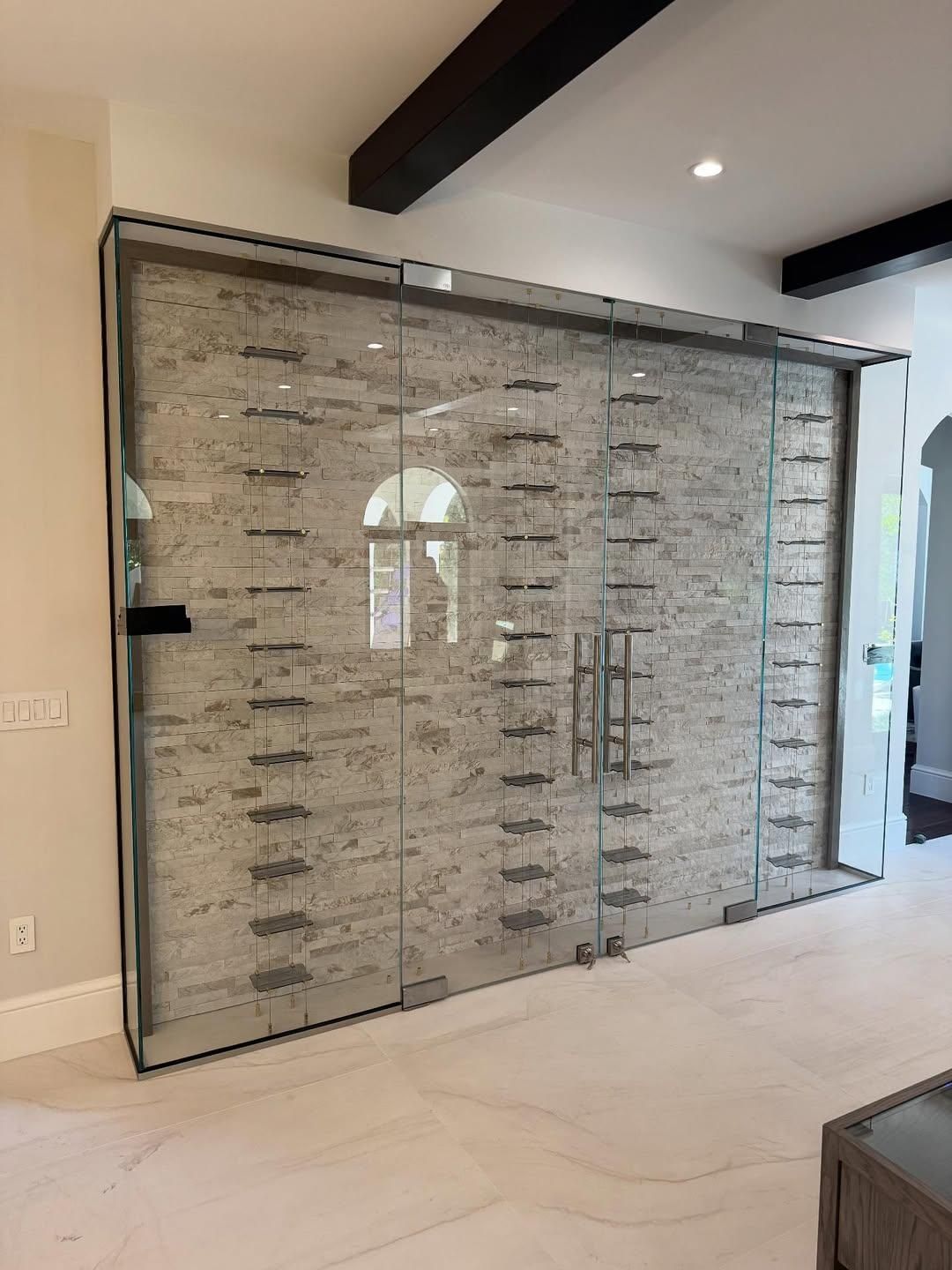 Large mirrored glass closet doors in a modern room with beige walls and wood ceiling beams