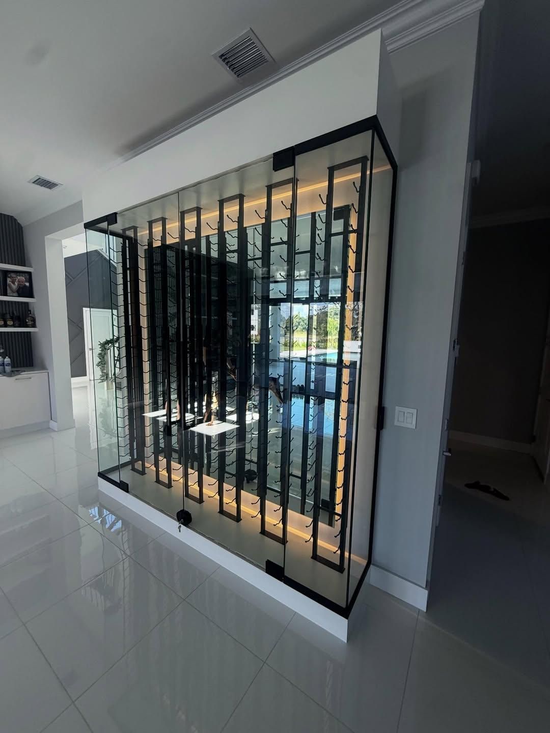 Modern hallway with a black metal security gate and glass partition beside a bright interior.