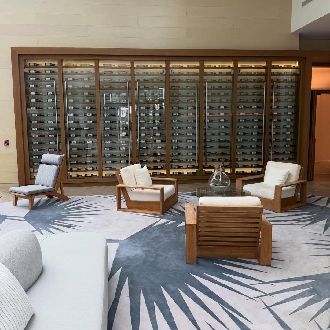 Modern lounge with four wooden chairs, a glass coffee table, and a wall of mail slots.