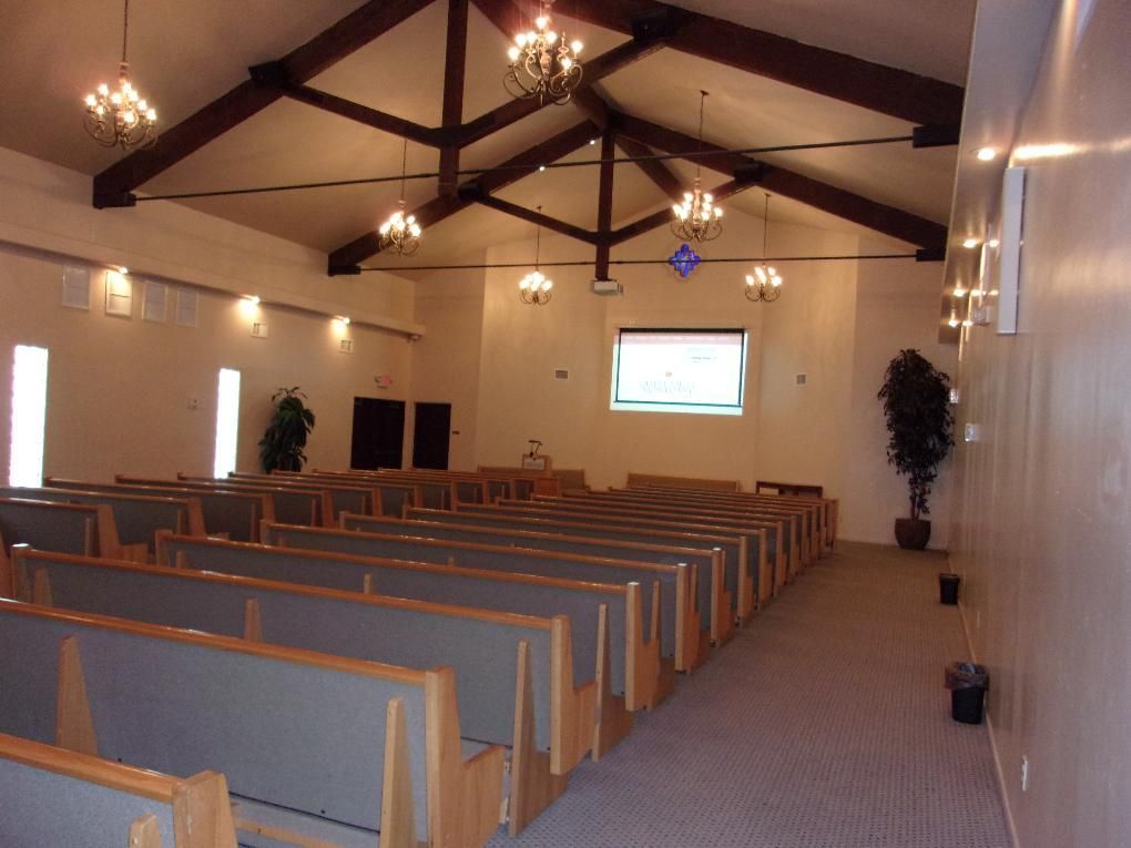 Empty church sanctuary with wooden pews, high vaulted ceiling, and a screen at the front